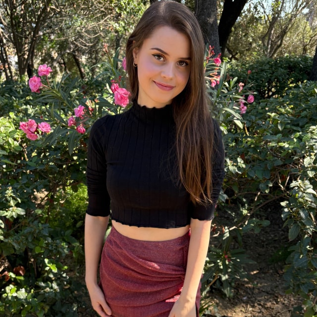 Jamie Young umgeben von rosa Blüten in einem Garten